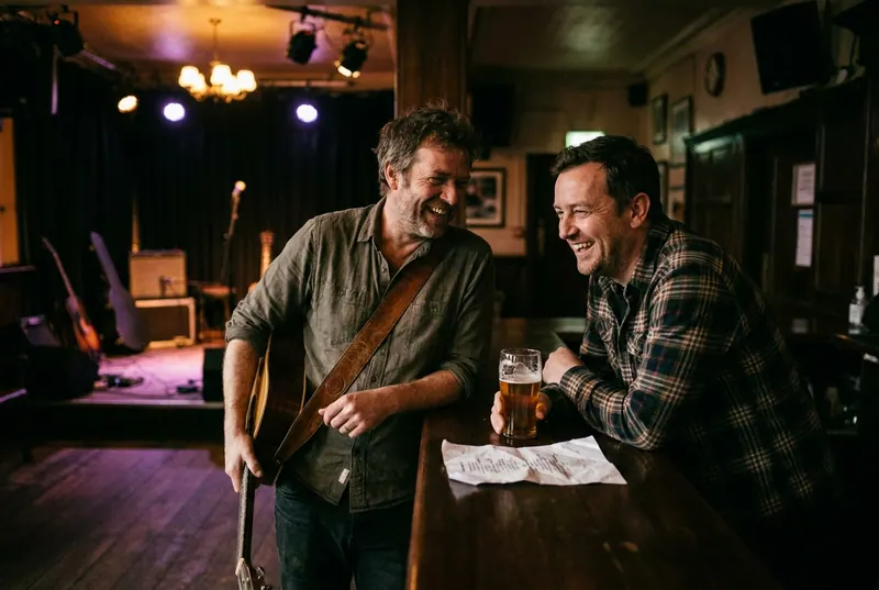 A venue manager and a musician talking at the bar after load-in