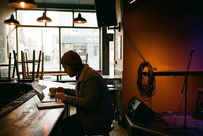 A venue manager working at the end of the bar in the afternoon, the room empty